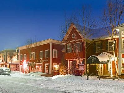 A snowy night with lights glowing in a small New England town